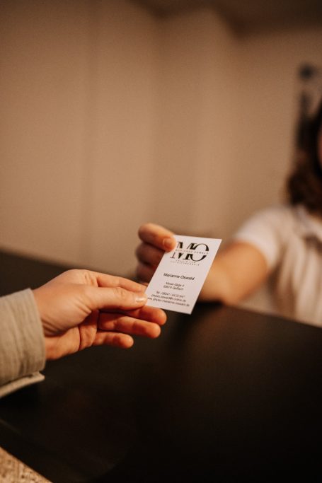 Physiotherapeutin übergibt Visitenkarte an eine Patientin an der Rezeption